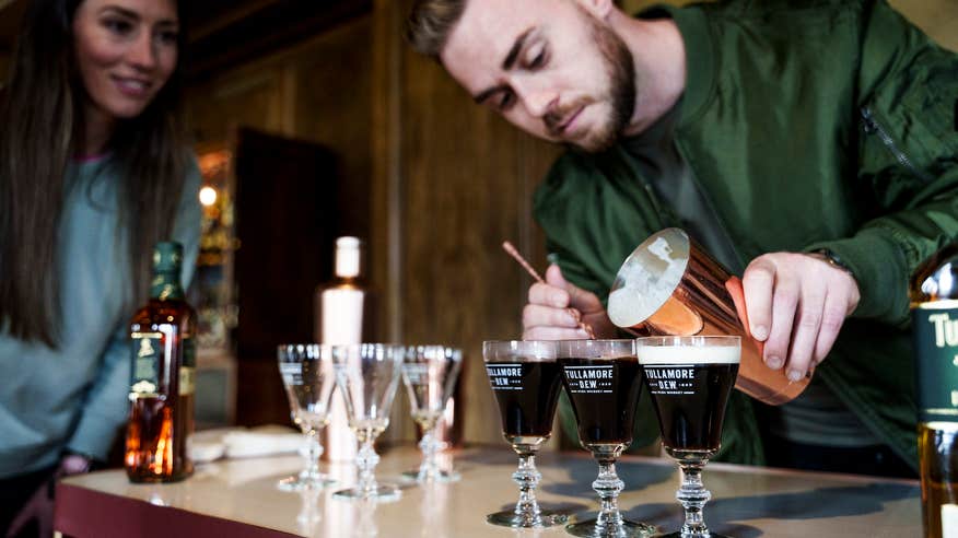 A man powering an Irish Coffee using Tullamore Dew.