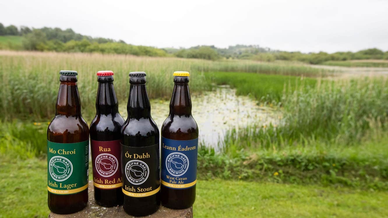 Four bottles of beer with branded labels with a lake view in the background