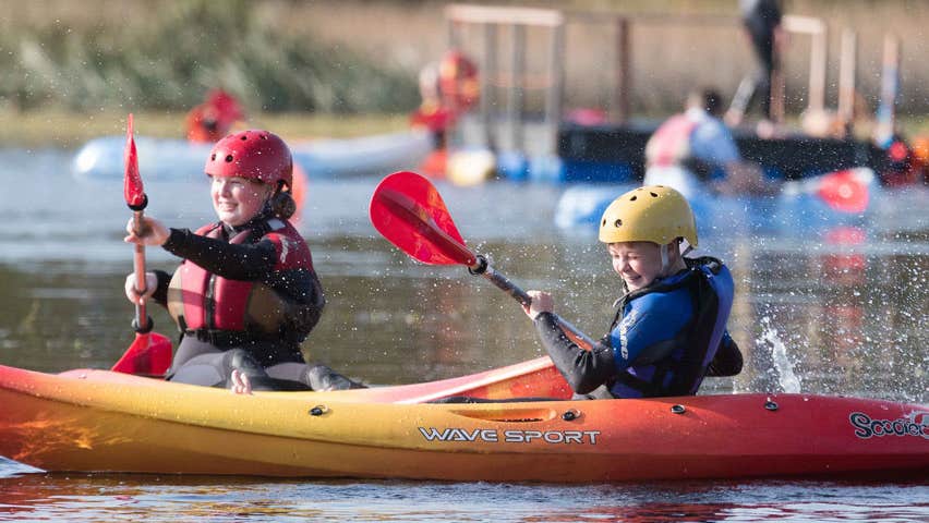 Two children on kayaks on a lake