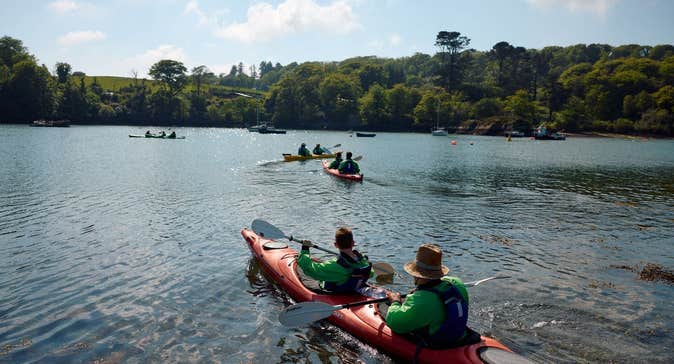 Kayakers on a lake lined with trees on a sunny day