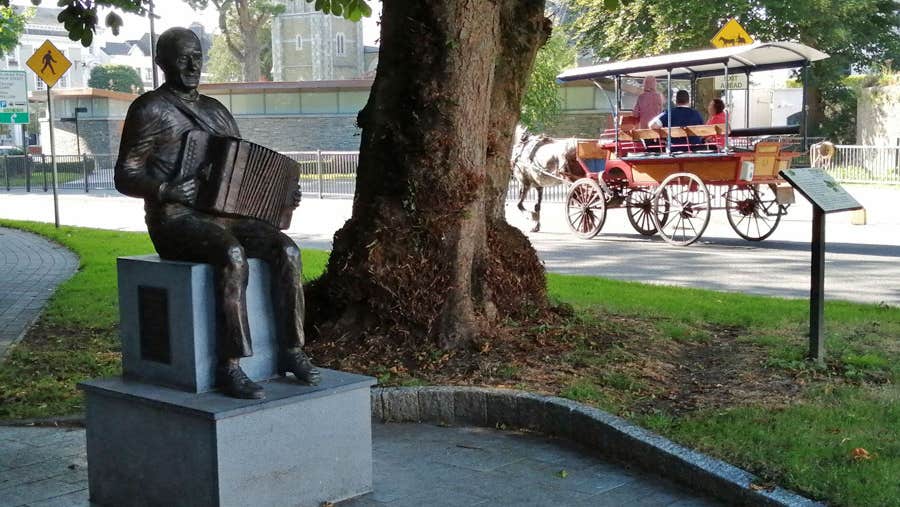 Bronze statue of local musician Johnny O'Leary captured in a seated position playing an accordion