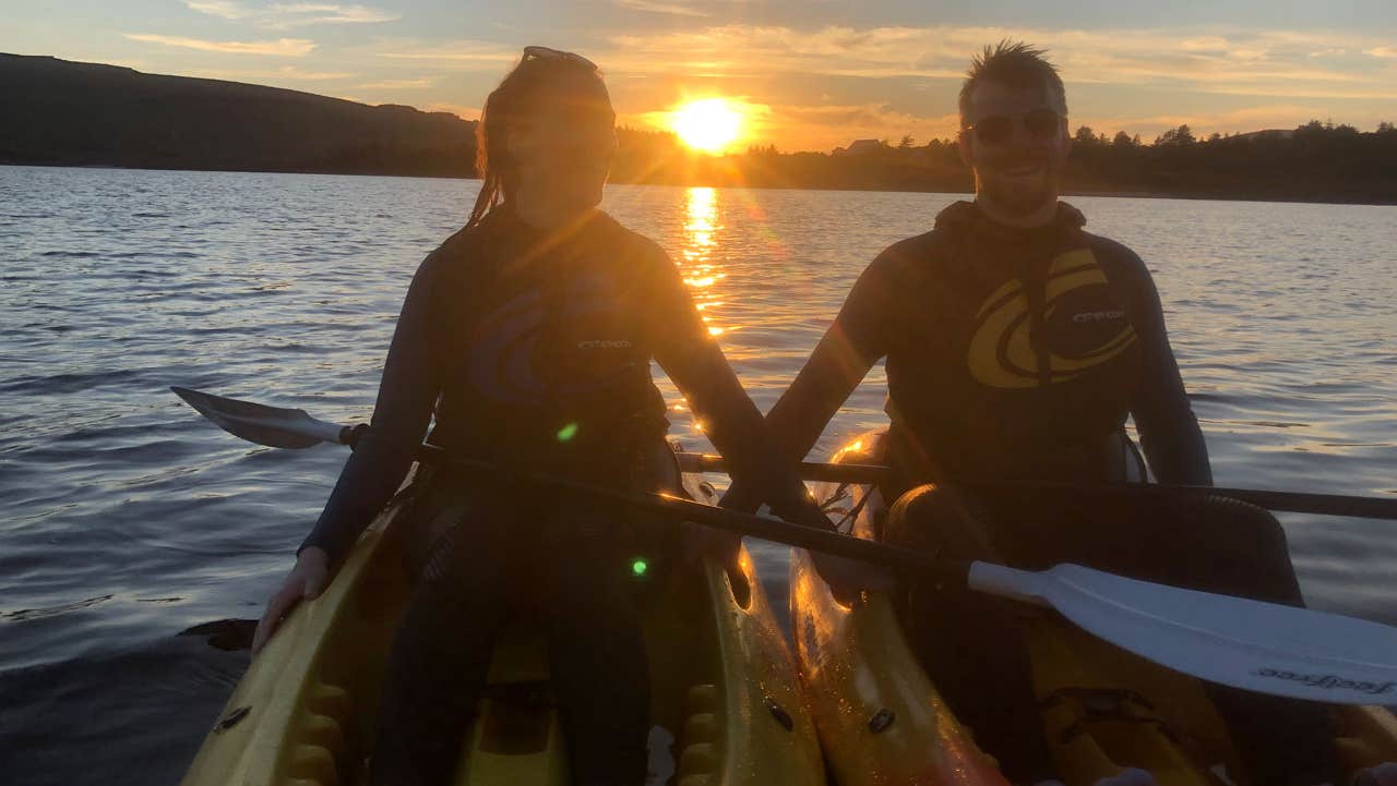 Two people out on kayaks with the sunset in the background