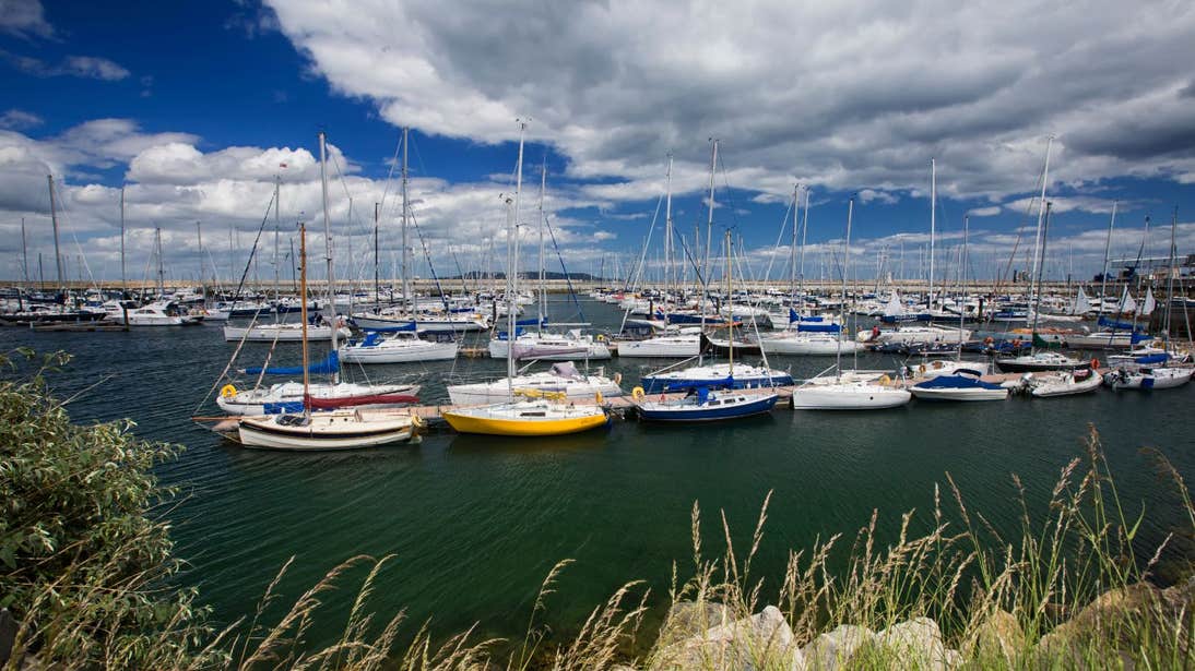 A blue sky fileld with clouds and boats bobbing along at Dún Laoghaire Harbour, Dublin