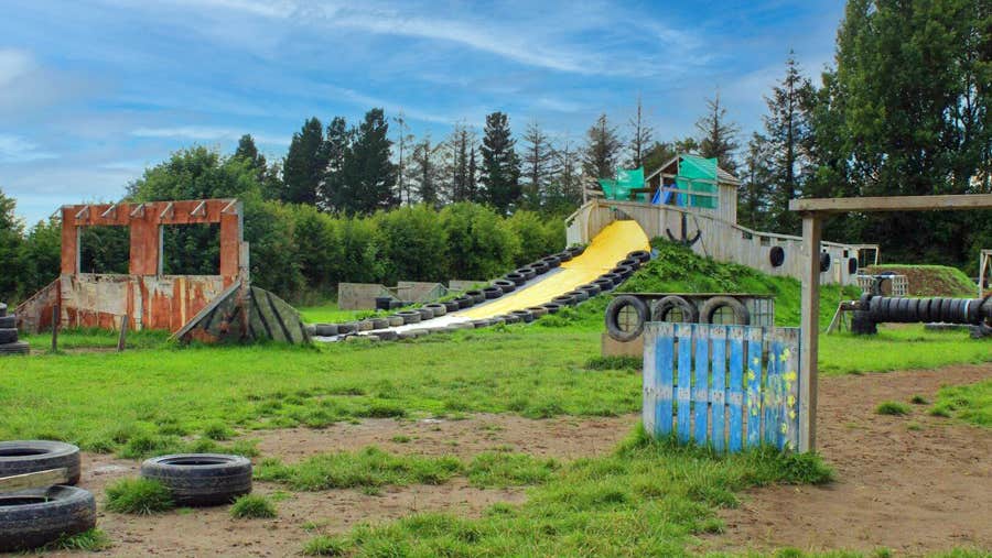Image of obstacle course with yellow slide, tyres and lookouts.