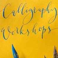 Bright yellow paper with fancy writing in shiny, blue ink and the nibs of pens at the bottom edge.