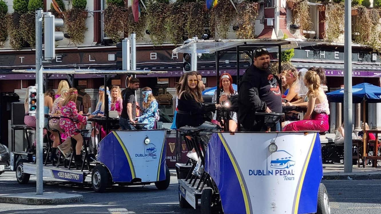A group riding two Dublin Pedal Tours bikes through a busy city street