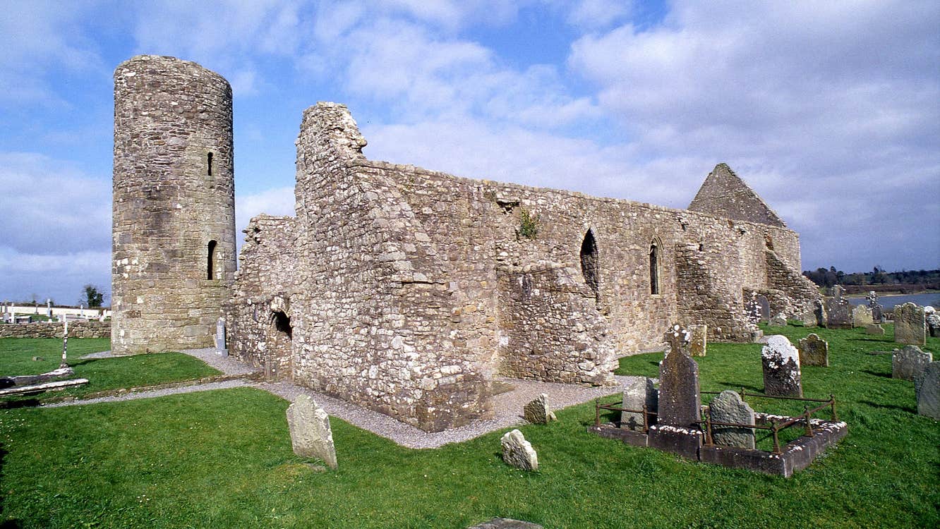 The ruins of an abbey with the remnants of a round tower beside it