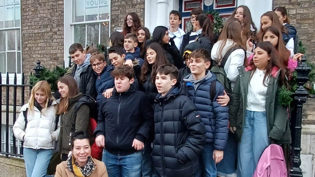 Group of teenagers and a tour guide posed on the steps of a Georgian house