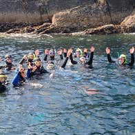 spike island ireland tours A group of snorkelers floating on sea surface waving their hands in the air