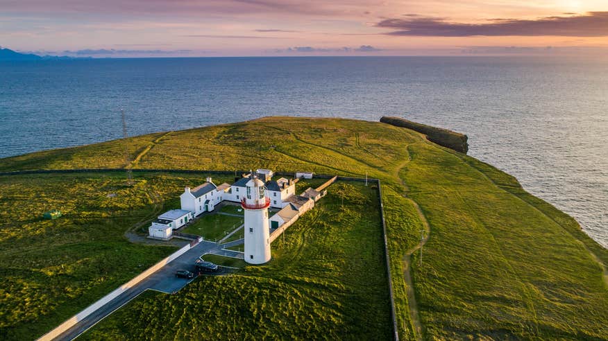 An aerial view of Loop Head Lighthouse from land at sunset