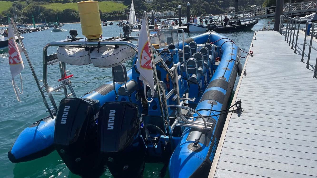 View of a blue rigid inflatable boat moored alongside a floating marina pontoon