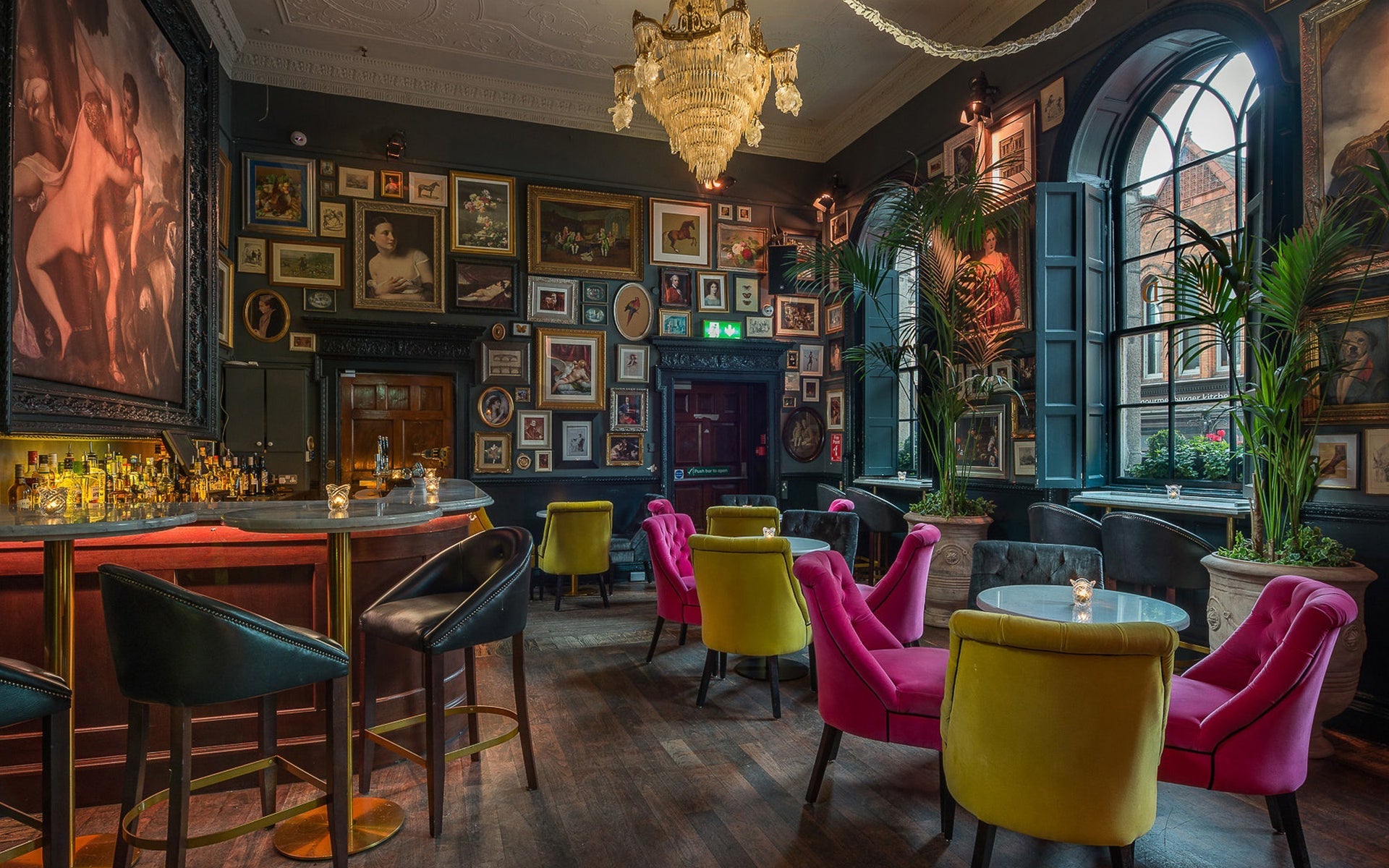 A bar with colourful seats, large window and wall to wall pictures of all sizes