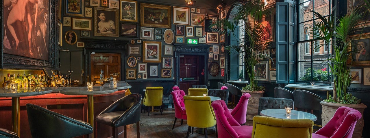 A bar with colourful seats, large window and wall to wall pictures of all sizes