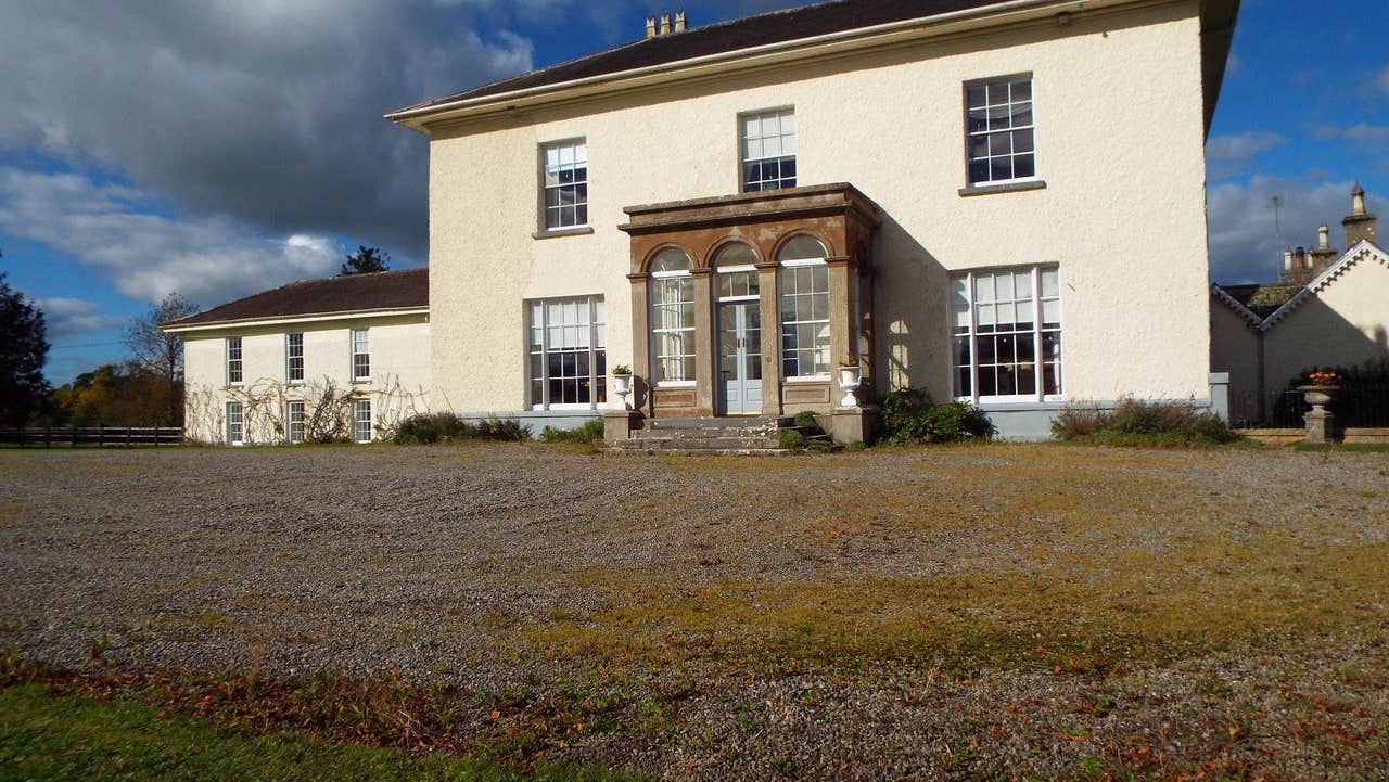 A small Georgian manor house overlooking a gravel driveway