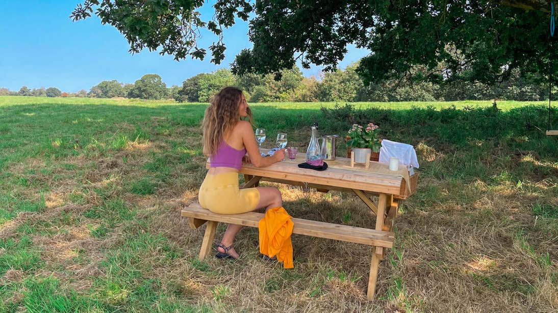 Roz Purcell sitting at a picnic table under a tree at Yew Point, Westmeath
