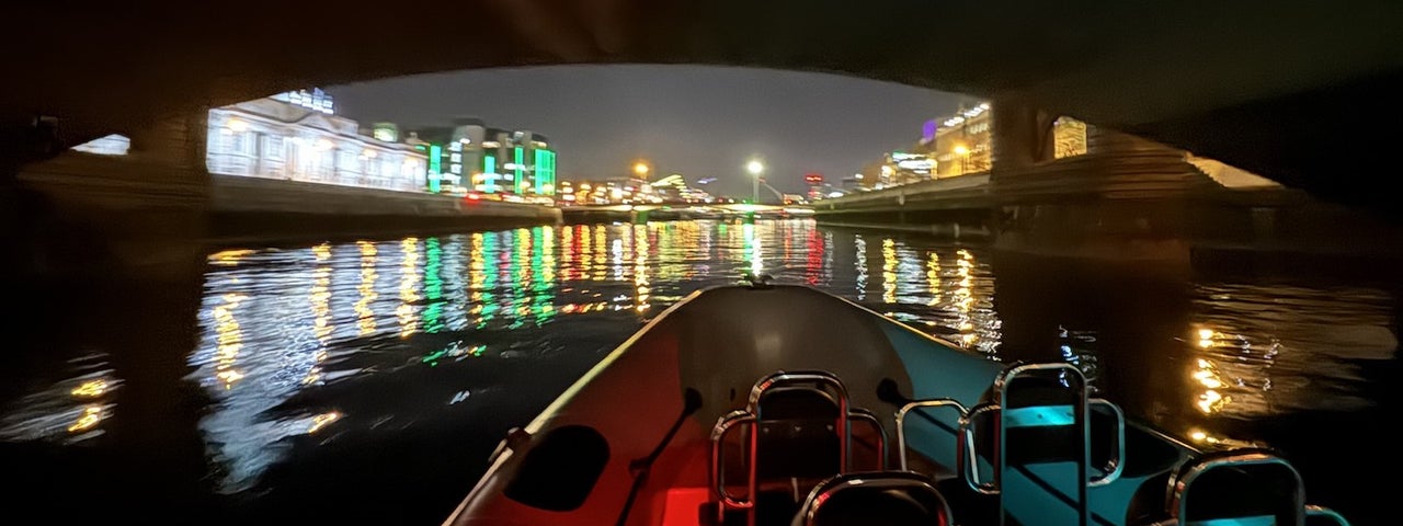 The Customs House comes into view as seen from Irish National Sailing and Powerboat School boat at night with building lit up.