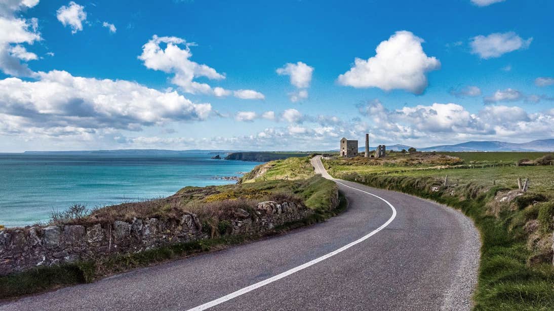 A coast road with a castle and stone buildings in the distance