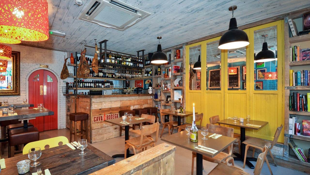 The interior of Cava Bodega restaurant featuring warm wooden furnishings and shelves of wine and books