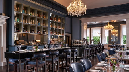 Elegant bar and lounge interior with chandeliers, high tables and a well stocked bar