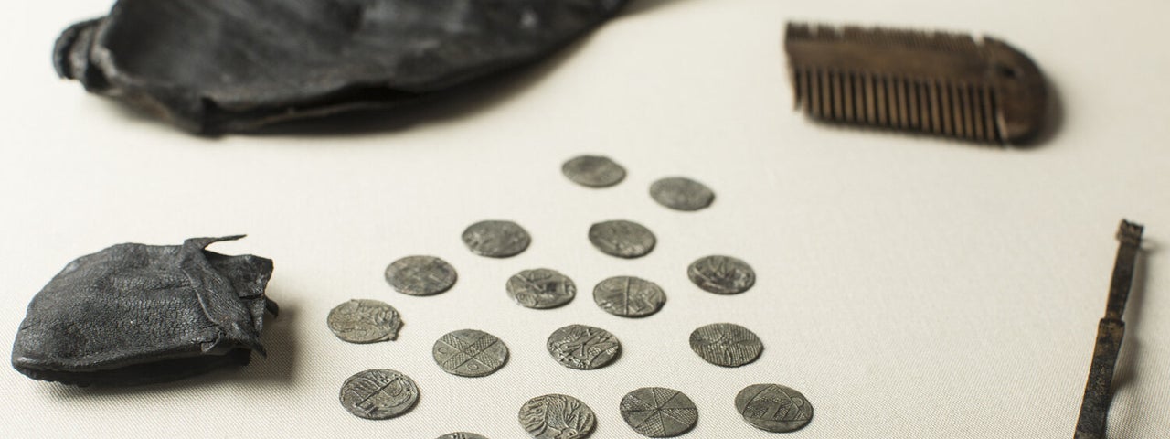 Viking coins spread over a tables from a leather pouch