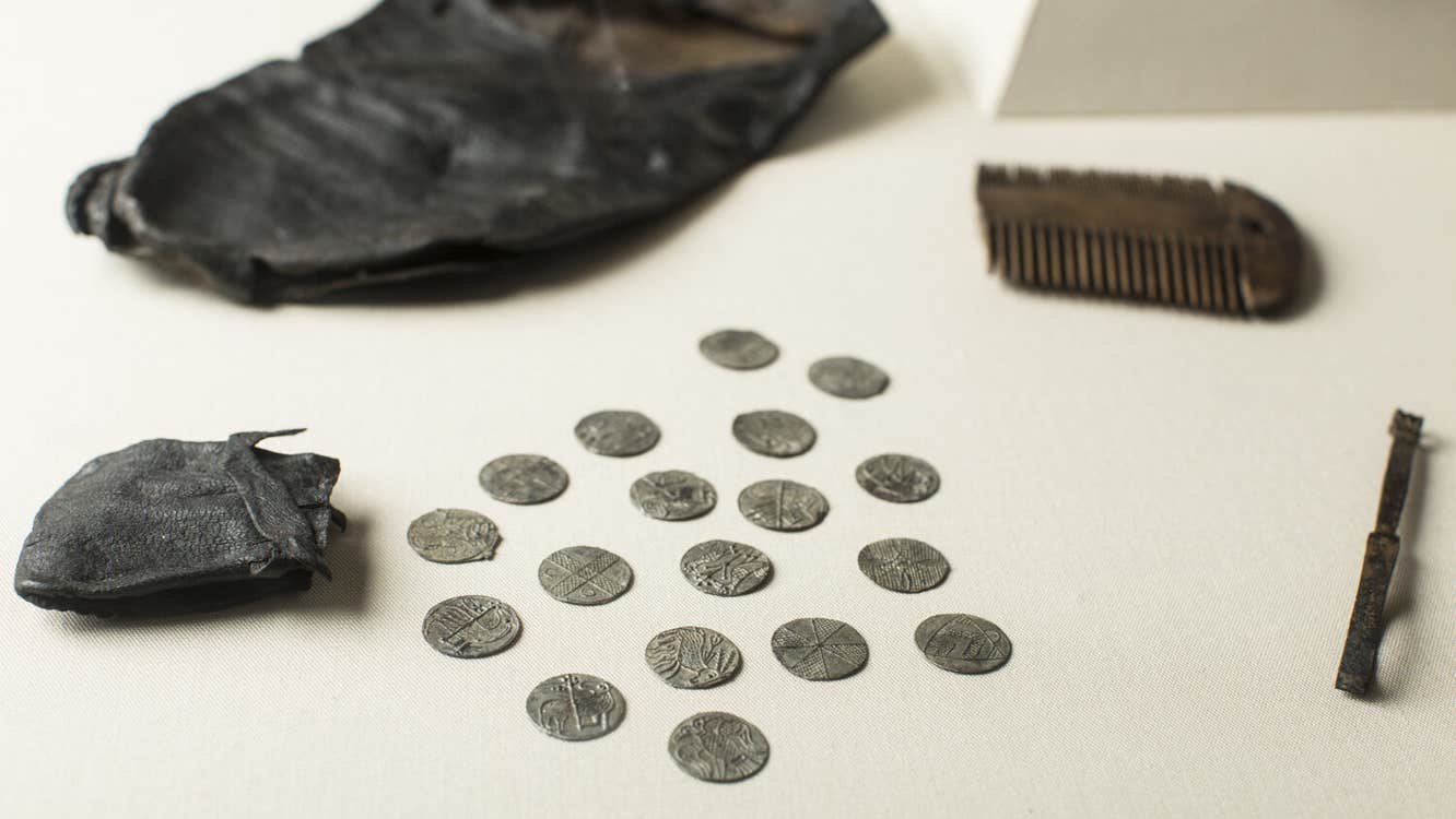 Viking coins spread over a tables from a leather pouch