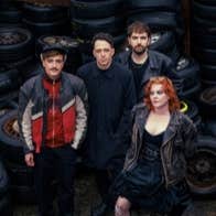 Group of 4 people standing close together surrounded by piles of old tyres and wheels