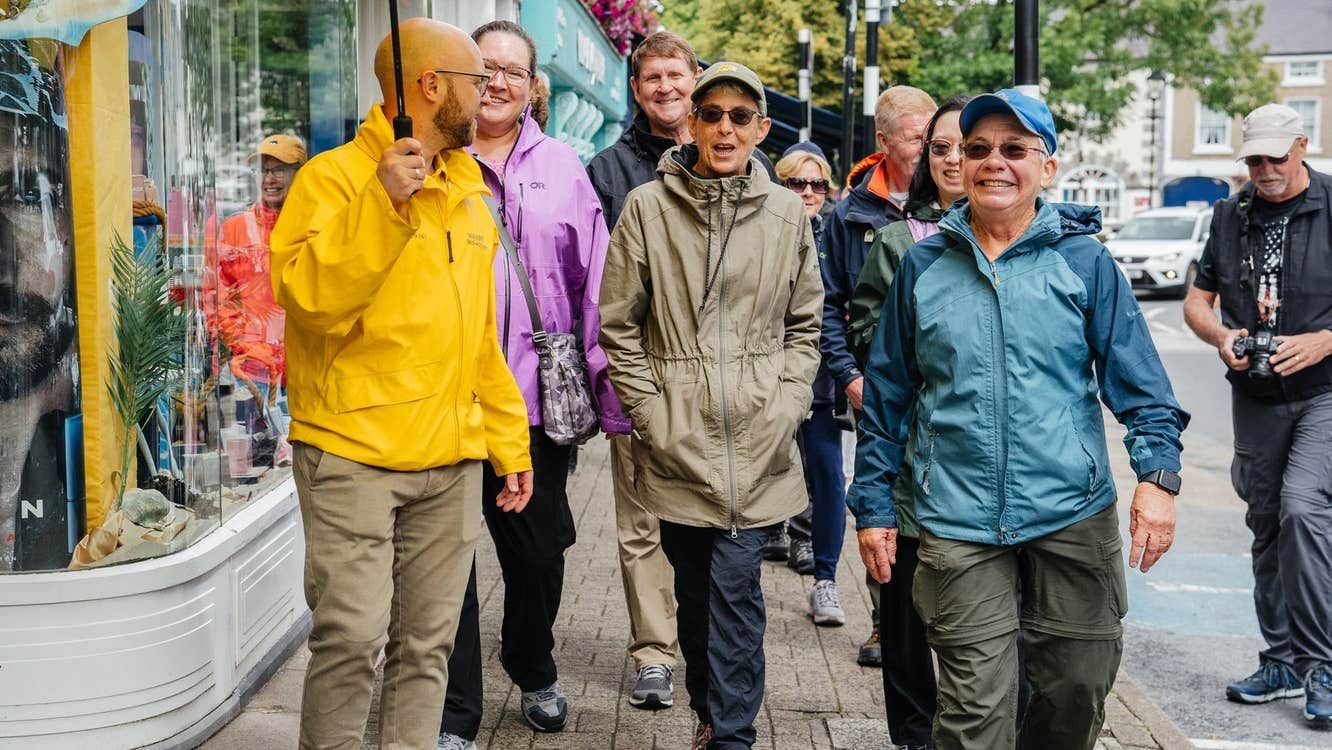 Guide holding an umbrella leading a group of smiling people