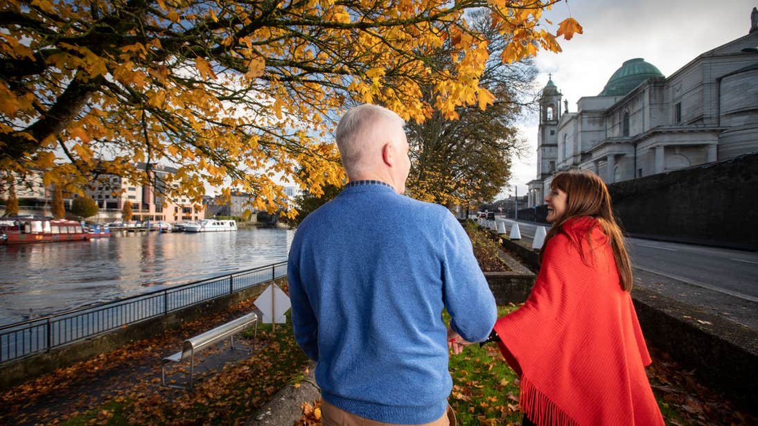 A couple holding hands walking along a tree-lined street in Athlone, County Westmeath