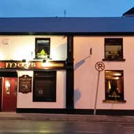 The exterior of Maggie Mays Restaurant in Loughrea on a darkening evening with the exterior lighting on