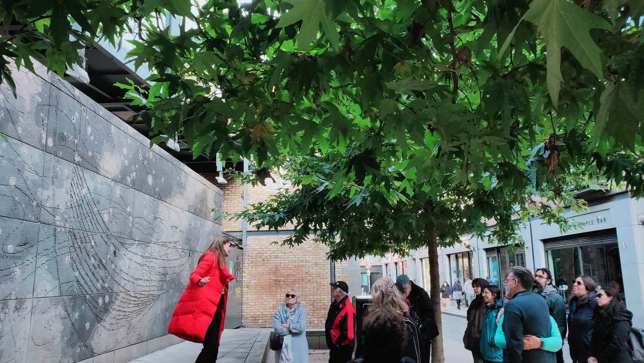 A tour guide speaking to a group of people at an ornate wall on a city street