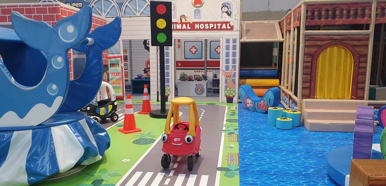 Toy vehicle on a fake road surrounded by colourful toys and play areas