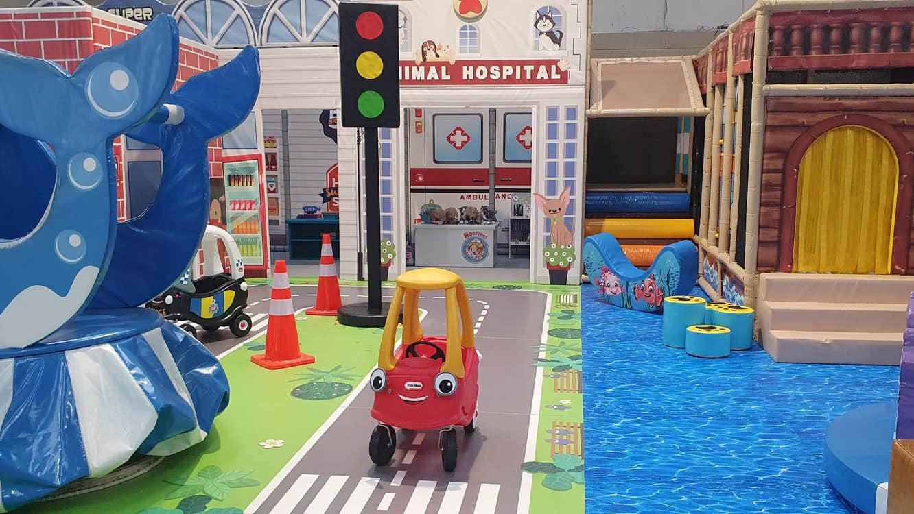 Toy vehicle on a fake road surrounded by colourful toys and play areas