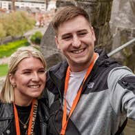 First Fortnight in partnership with St Patrick's Cathedral, 2 smiling people taking a selfie up high in stone building with blurry view of city below