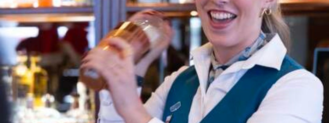 A smiling bartender is shaking a cocktail maker.