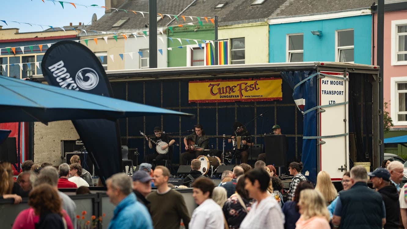Dungarvan TuneFest 2026, people dancing outside in a town square with trad band playing on small stage.