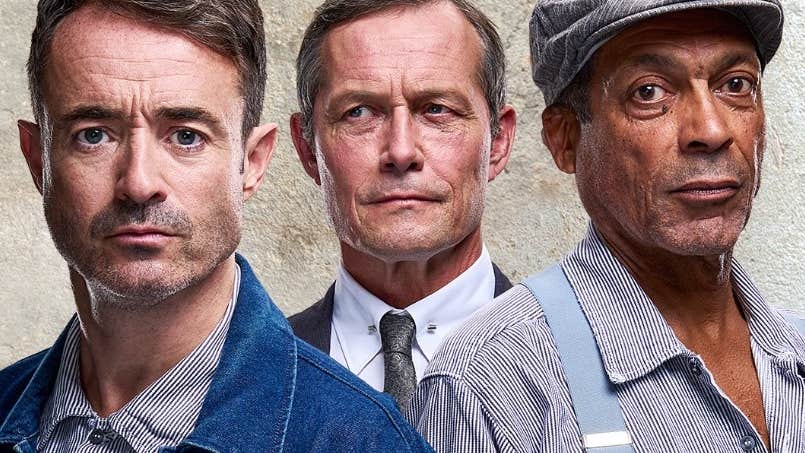 Headshots of 2 men in denim and stripy old shirts with man behind in formal shirt, tie and suit.