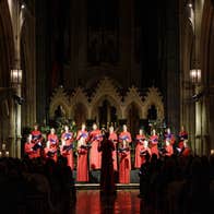 Christmas with Christ Church Cathedral choir, dressed in long red gowns standing in front of an alter