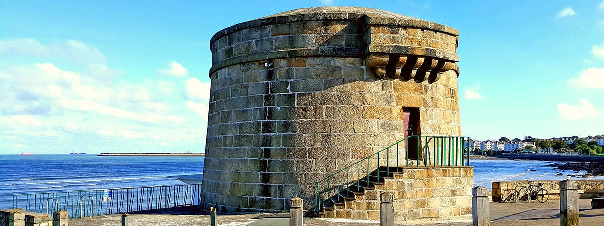 Martello tower with blue sea and blue and white clouds in the background