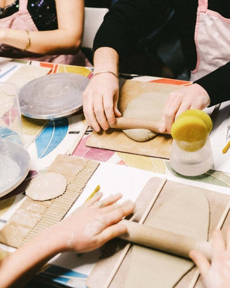 Looking down at table with hands rolling slabs of clay