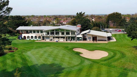 The clubhouse from a distance and a height with a sand dune in the foreground of the picture