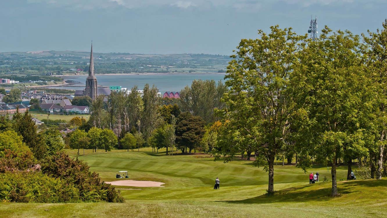 Wexford Golf Club view of a golf green with a church and the harbour in the background