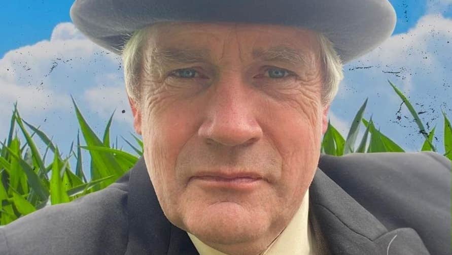 A man in a grey hat and jacket looking intent.