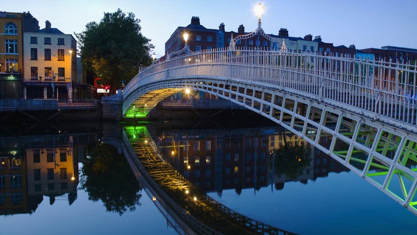 A bridge spanning a river in a city at dusk