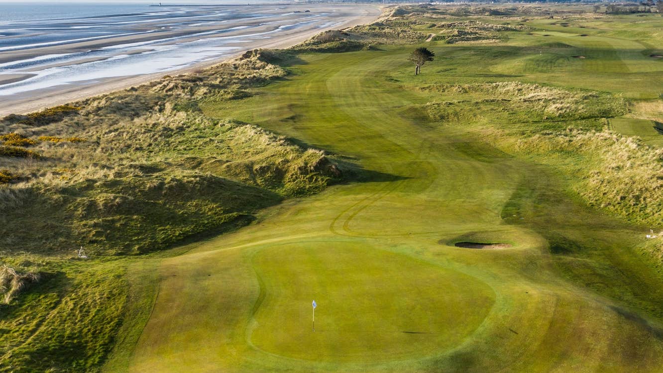 Aerial view of golf green with a beach to the left