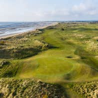 Aerial view of golf green with a beach to the left