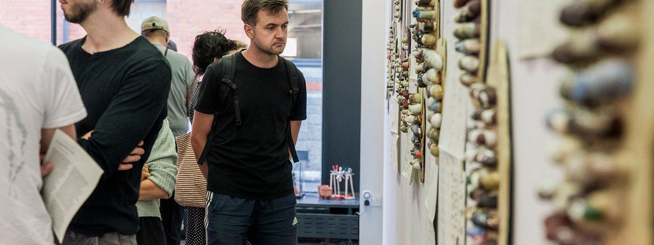 A man stands in a Gallery looking at art on the wall