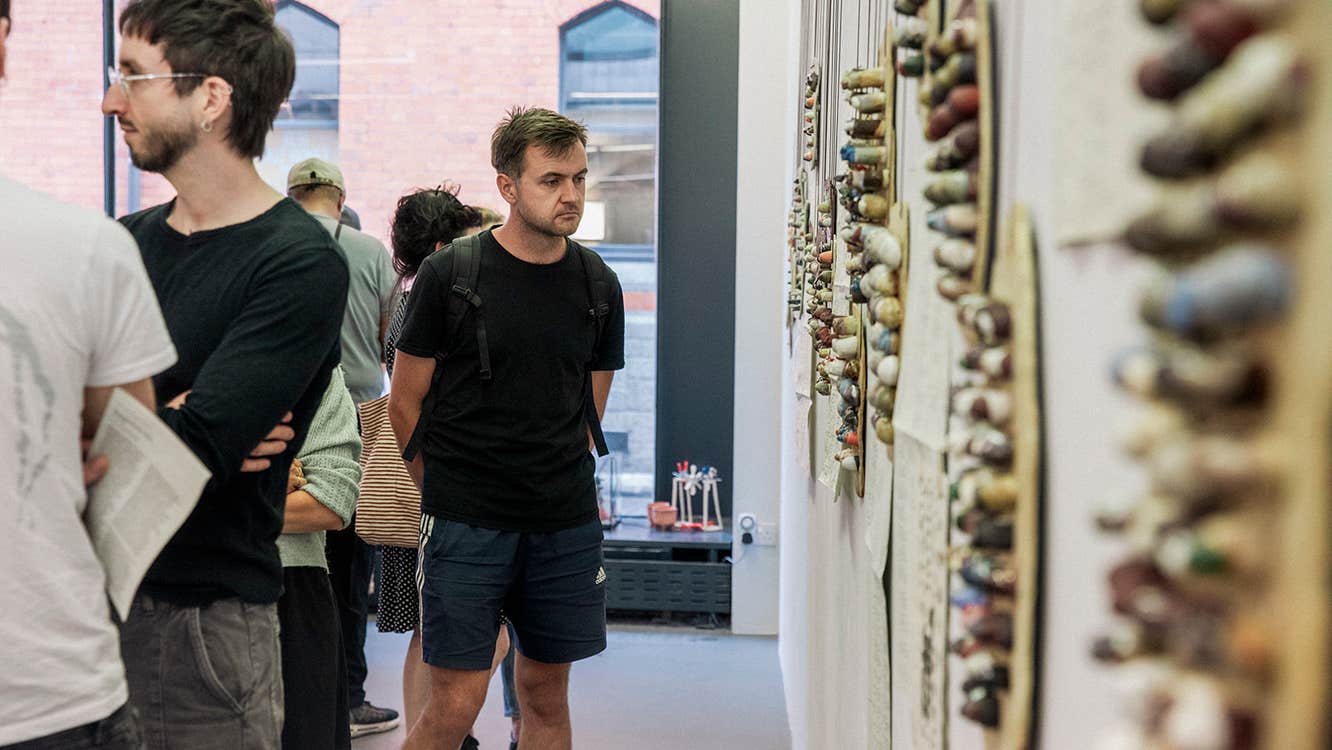 A man stands in a Gallery looking at art on the wall