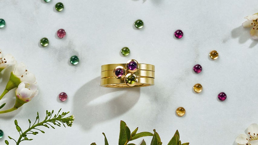 Image of gold ring with three stones and lots of coloured gems.