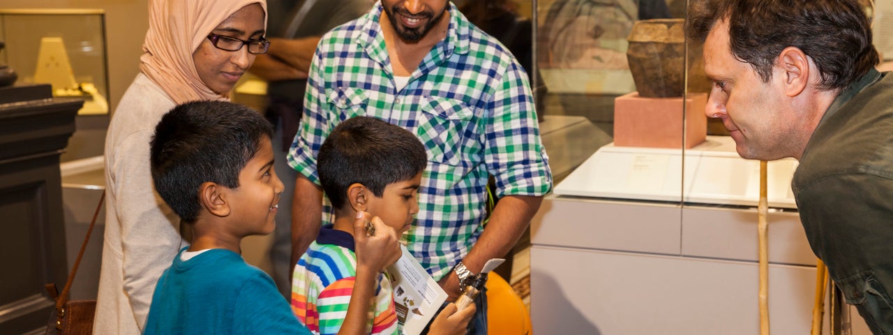 Drop-In: Stone Age Handling Workshop in the Learning Resource Room - a family looking at old artefacts on a table