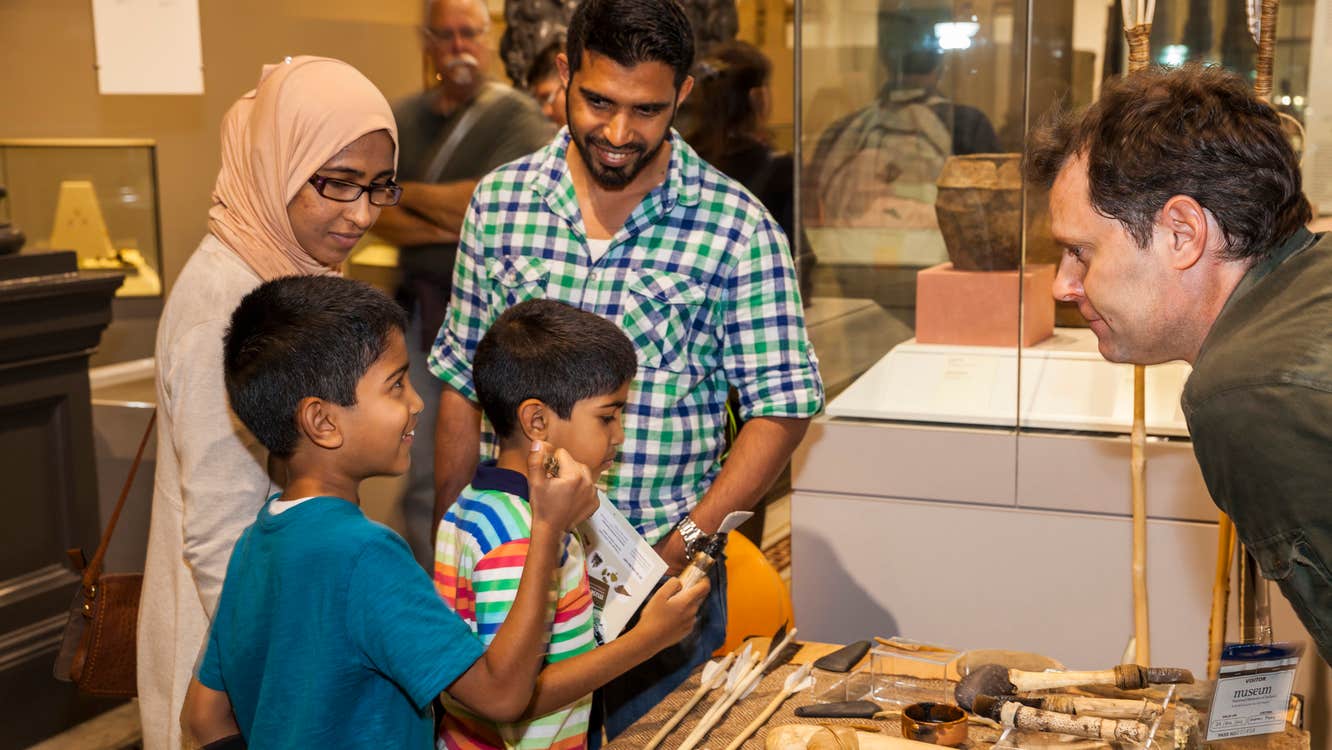 Drop-In: Stone Age Handling Workshop in the Learning Resource Room - a family looking at old artefacts on a table